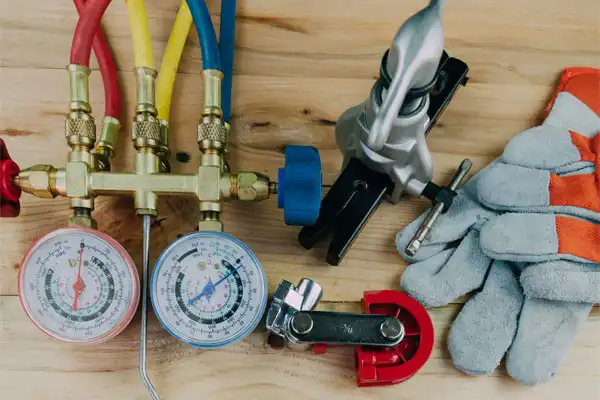 A selection of Coast to Coast HVAC tools—manifold gauge, hoses, pipe cutter, swaging tool, gloves—ready for service on-site.